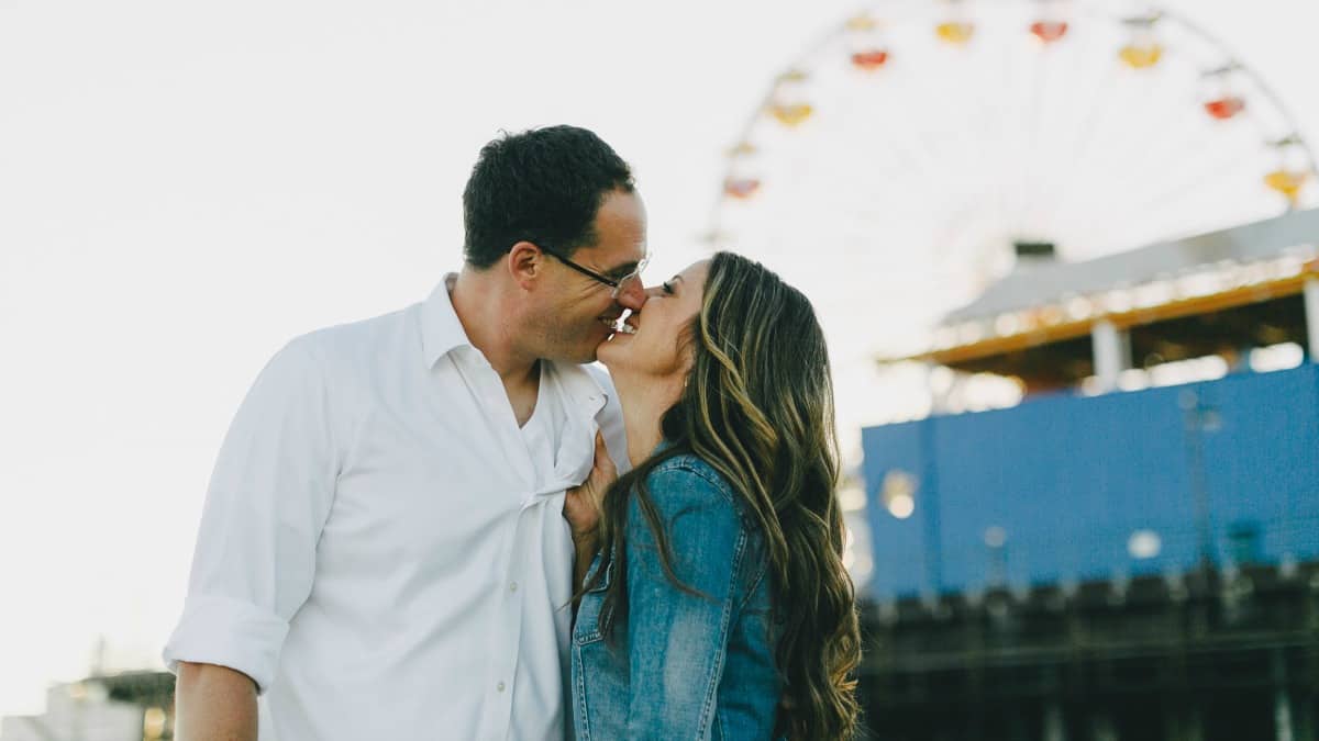 couple kissing with ferris wheel in background on Valentine's Day