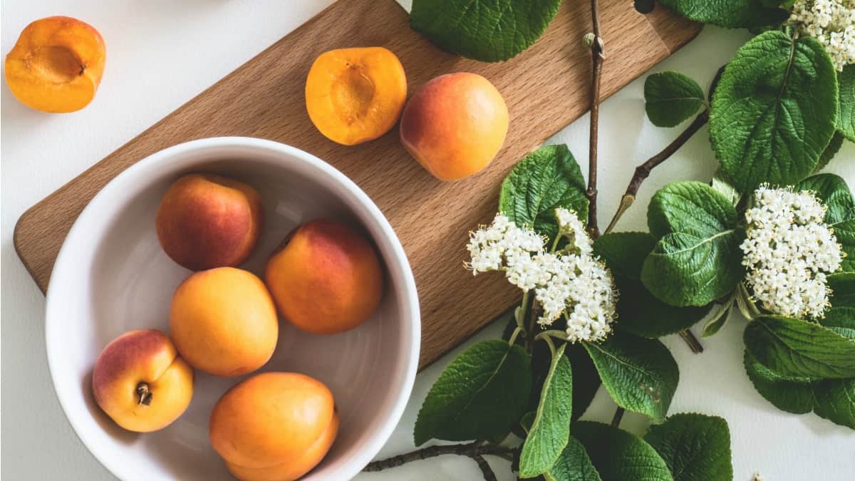 spring food peaches in a bowl with a cutting board and flowers