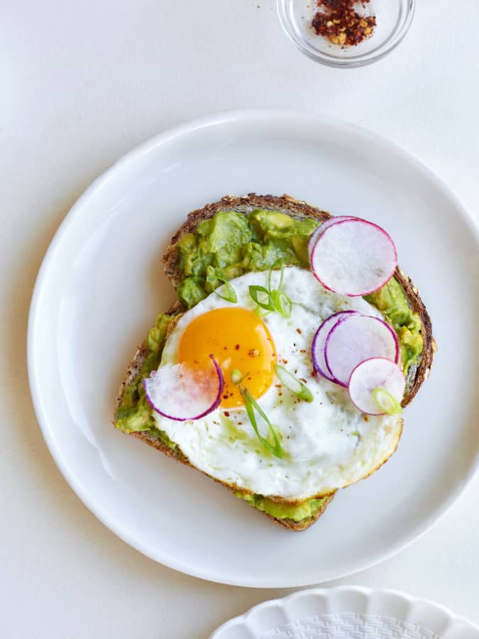avocado toast with fried egg aerial view with garnishes