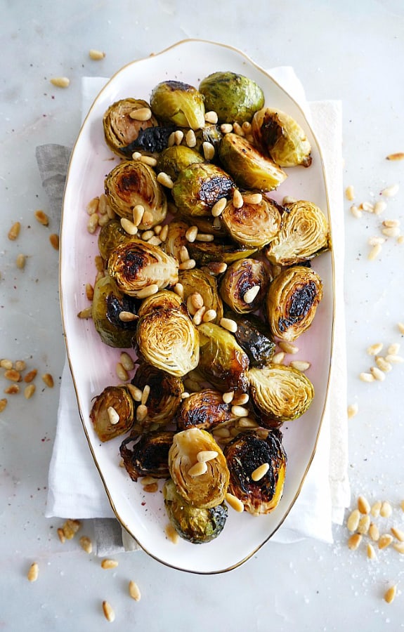 Apple Cider Roasted Brussels Sprouts with pine nuts on white dish