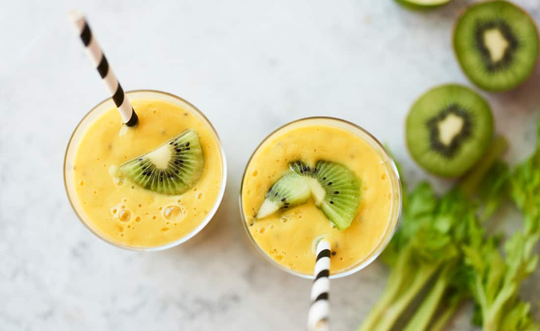 mango kiwi kefir lime smoothie image with kiwi, yellow smoothie in cup with straws