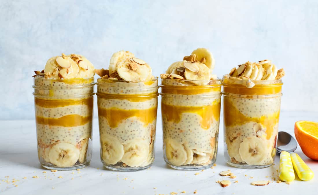 chia seed pudding in mason jars with layers of orange, banana, and yogurt