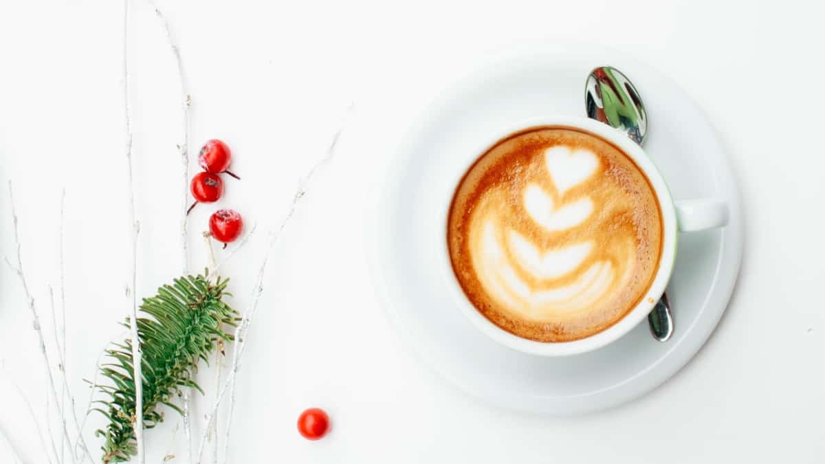 holiday coffee drink latte with mistletoe and cranberries on marble