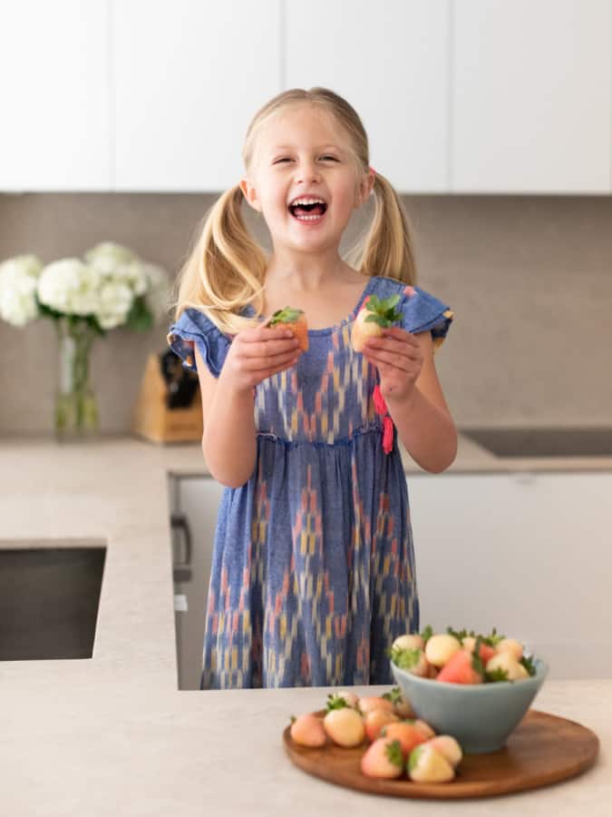 little girl holding pineberries in kitchen