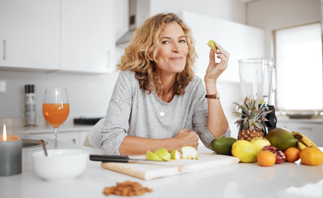 Woman eating fruit at kitchen counter